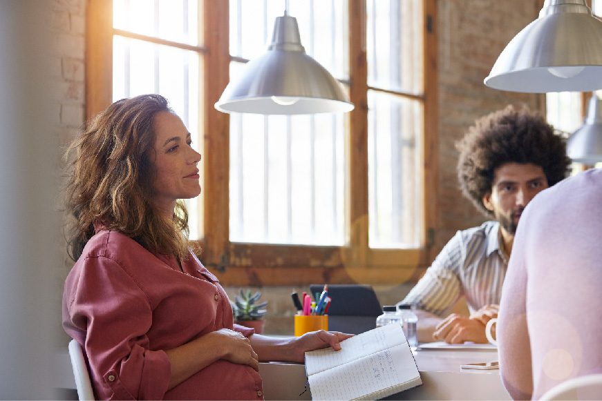 three people sitting at a table having a discussion